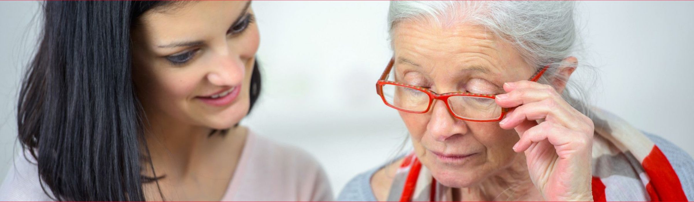 Pflegekraft mit Seniorin mit roter Brille